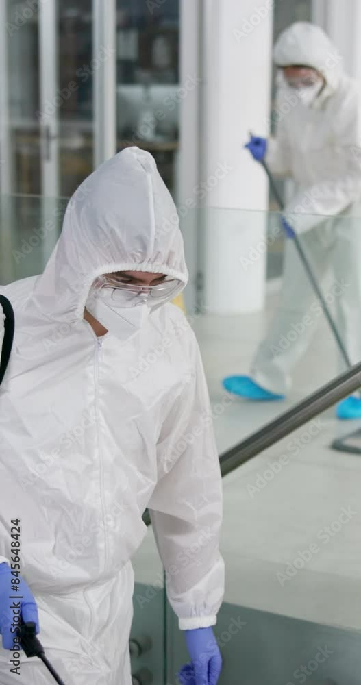 Man, white suit and spray chemical for sanitation on stairs, pandemic or disinfection for virus protection. Person, bottle or lockdown for illness spread in office, cleaning with mask for policy Man, white suit and spray chemical for sanitation on stairs, pandemic or disinfection for virus protection. Person, bottle or lockdown for illness spread in office, cleaning with mask for policy