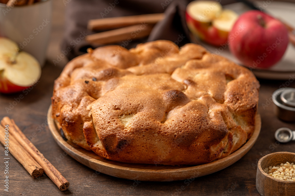 Traditional apple pie on a wooden plate on a dark culinary background. Charlotte pie on a platter in close-up. Delicious homemade cakes on the kitchen table