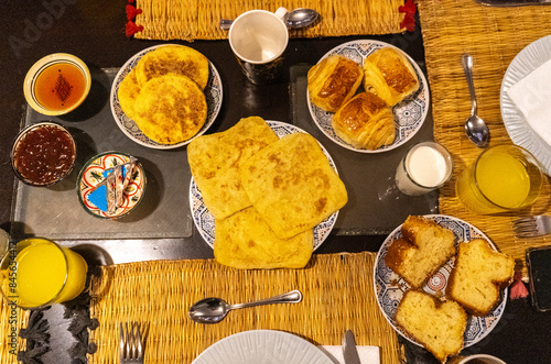 Moroccan breakfast ftour, msemen, baghrir, orange juice, pastries, bread basket, fried eggs, cheese cubes photo