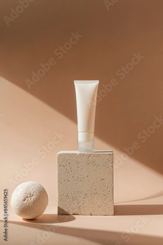Off-white pieces of stone rocks with blank tube for mock-up product presentation. Mock-up for exhibitions or presentation of cosmetic products or packaging with natural stones, dramatic lighting