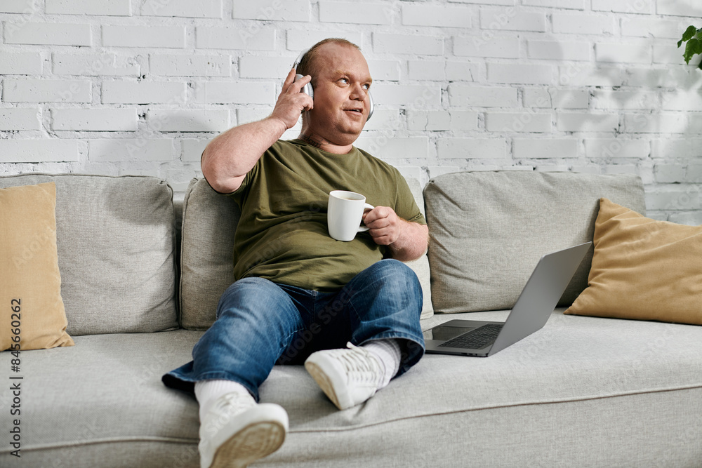 A man with inclusivity sits comfortably on a couch, wearing headphones and enjoying a cup of coffee. A man with inclusivity sits comfortably on a couch, wearing headphones and enjoying a cup of coffee.