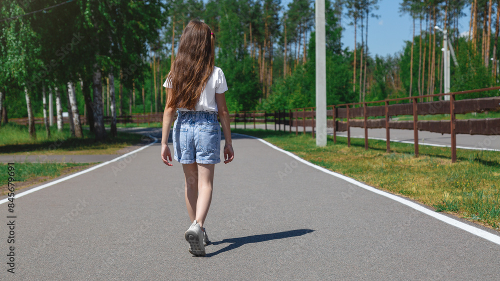 Positive pretty little girl going road on park in the white t-shirt and jeans shorts sunny weather warm season. Positive pretty little girl going road on park in the white t-shirt and jeans shorts sunny weather warm season.