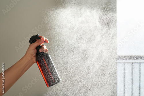 Foto A woman's hand sprays an air freshener in a room.