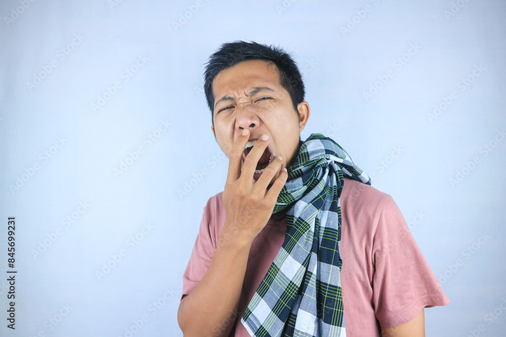 Tired young indonesian man wearing a sarong and yawning, feeling sleepy. Bedtime concept Tired young indonesian man wearing a sarong and yawning, feeling sleepy. Bedtime concept
