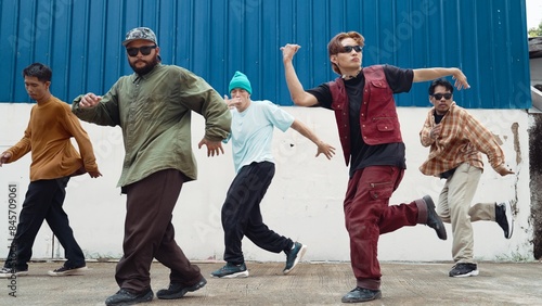 Group of hip hop choreographer dancing street dance together at wall. Young break dancer practicing break dance, moving to modern rhythm, express feeling of lively. Outdoor 2024. Endeavor.