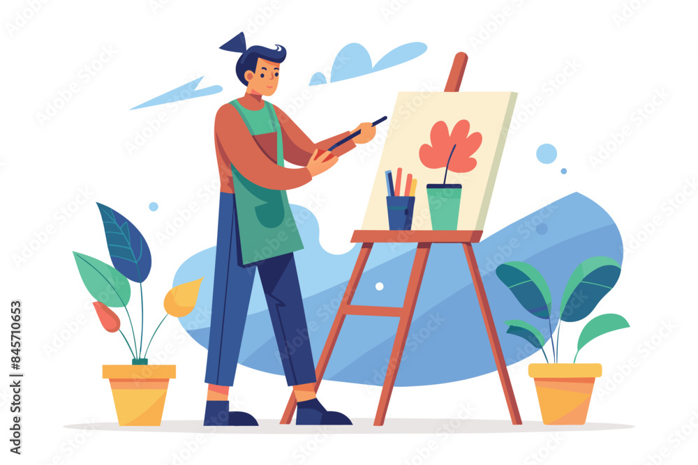 Fototapeta premium A young artist with a green apron is painting a flower on a canvas easel in their studio. There are potted plants on either side of the easel.