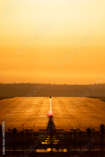 Helsinki, Finland - May 30st 2024: Airport marshaller vehicle on the runway centerline inspecting. Sunrise, golden sky and warm light, early morning. Helsinki-Vantaa International