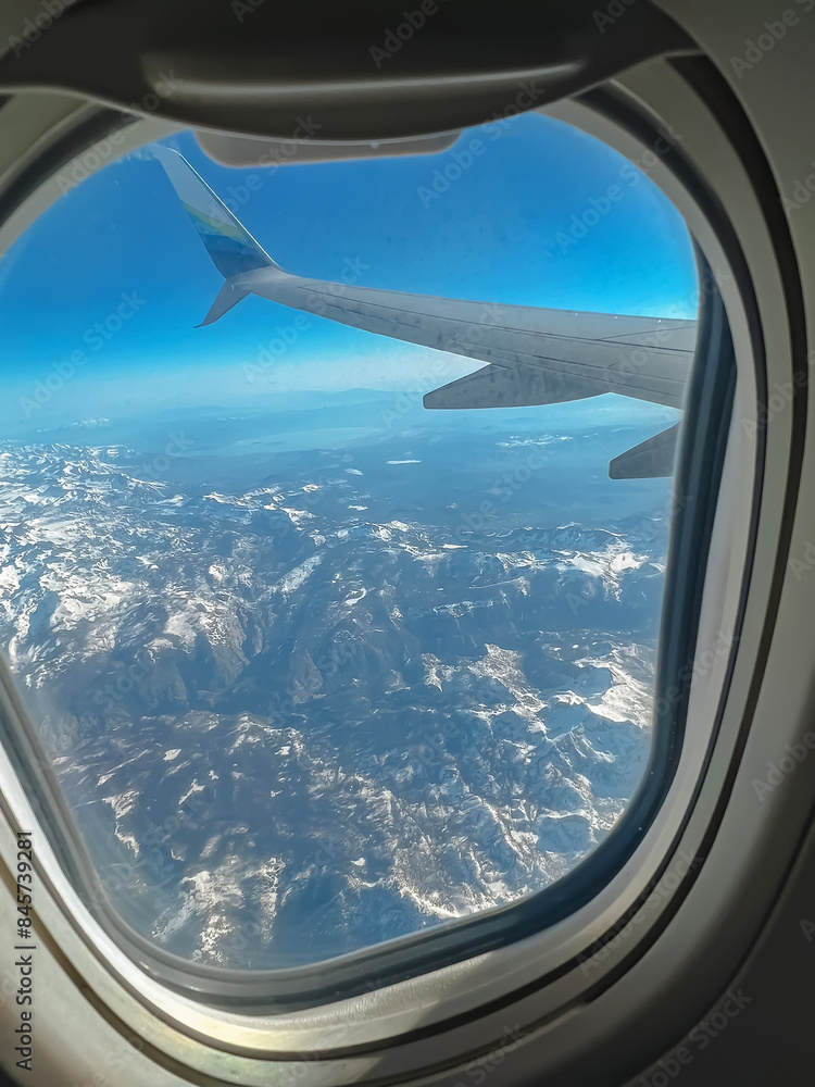 View of the snowy mountains from the plane window View of the snowy mountains from the plane window