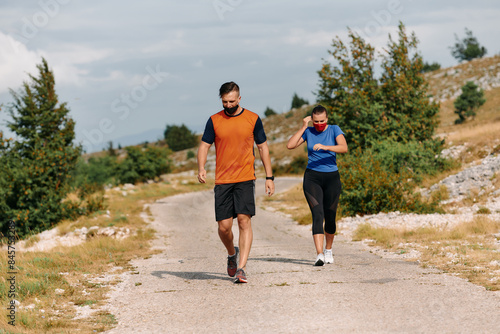 Couple running in nature at morning wearing protective face masks