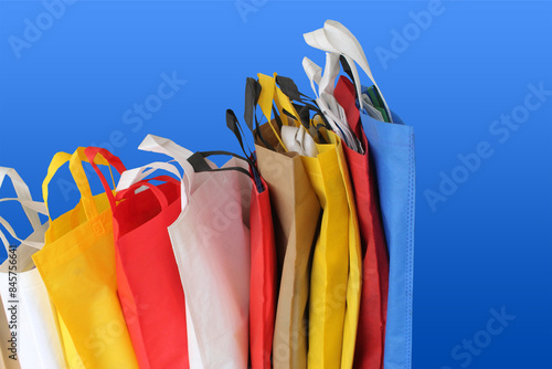 Beautiful Non Woven grocery shopping bags with blue background. Assorted Colors Eco friendly bags with copy space for text. pile of textured and porous polypropylene material. partially sighted image photo