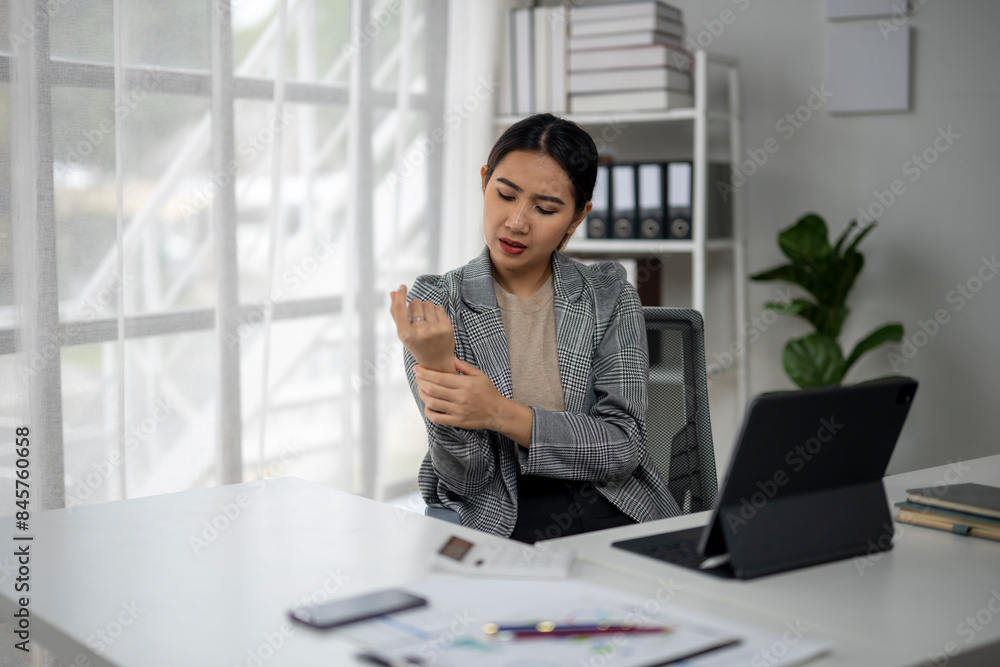 A woman in a business suit is sitting at a desk with a laptop and a cell phone A woman in a business suit is sitting at a desk with a laptop and a cell phone