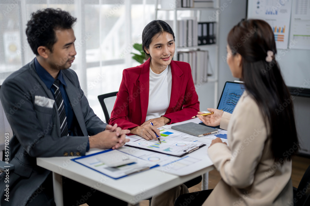 Three people are sitting at a table, discussing something Three people are sitting at a table, discussing something