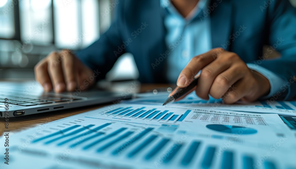 Analyzing financial data on laptop and documents Analyzing financial data on laptop and documents