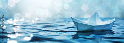 Paper boat sailing on blue boundless water. Small white origami boat In big ocean with blue sky and sunshine. Leadership concept with paper ship. Business for innovative solution. Opportunity, vision. photo