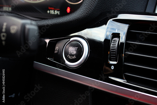 Close up engine car start button in dashboard. Car start stop system button in car interior. Car Ignition Key. Black Start stop engine button in modern SUV. 