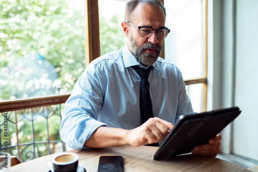 Businessman in a cafe working with tablet and drinking coffee Businessman in a cafe working with tablet and drinking coffee