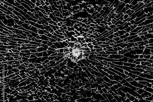 фотографія Texture of broken tempered glass with a bullet hole and diverging cracks on a black background