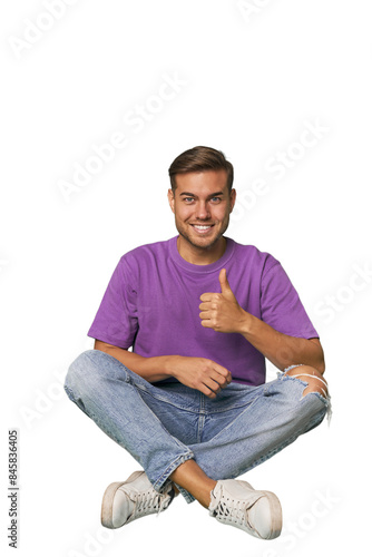 Casual man sitting on floor smiling and raising thumb up