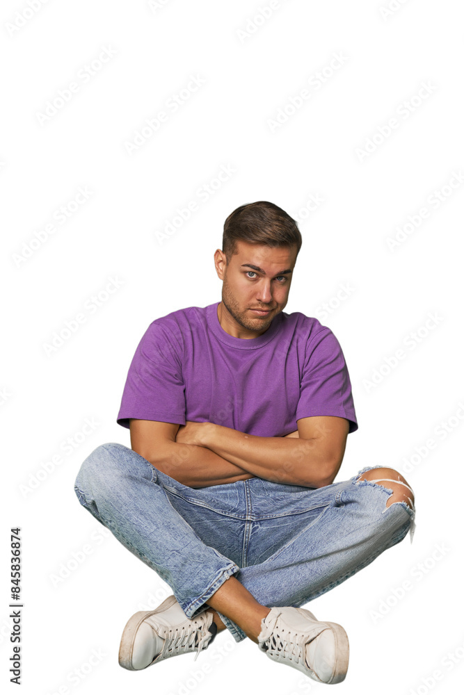 Casual man sitting on floor suspicious, uncertain, examining you. Casual man sitting on floor suspicious, uncertain, examining you.