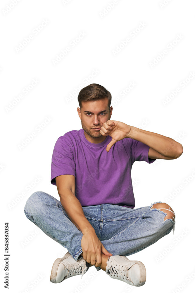 Casual man sitting on floor showing thumb down, disappointment concept. Casual man sitting on floor showing thumb down, disappointment concept.