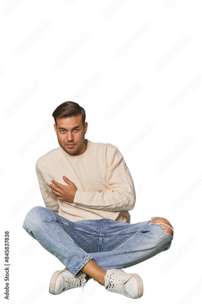 Young Caucasian man sitting on the floor in a studio setting Young Caucasian man sitting on the floor in a studio setting