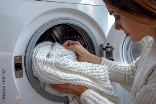 Partial portrayal of hand removing a thick white sweater from a washing machine, depicting part of a washing routine photo