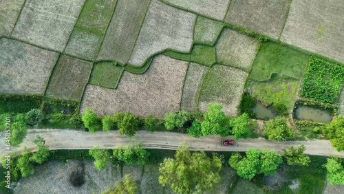 Aerial shot of agricultural tractor with crop seeder attached driving along dirt road through plowed fields and polluted landscape drone pov directly aboveAerial drone bird eye view of Gazipur Dhaka photo