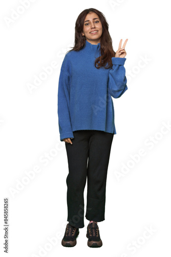 Middle Eastern woman, full body studio joyful and carefree showing a peace symbol with fingers.