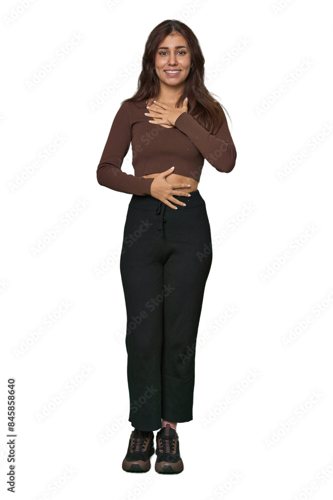 Middle Eastern woman, full body studio laughs happily and has fun keeping hands on stomach. Middle Eastern woman, full body studio laughs happily and has fun keeping hands on stomach.