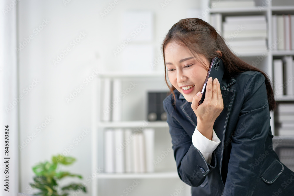 Businesswoman in a modern office, smiling while talking on her phone. Professional environment with bookshelves in the background. Businesswoman in a modern office, smiling while talking on her phone. Professional environment with bookshelves in the background.