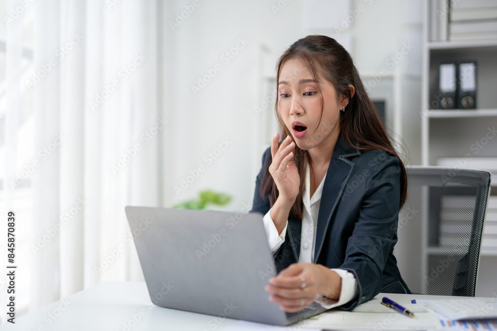 Businesswoman in a suit surprised while working on laptop in office, expressing shock or amazement, concept of business or work surprise reaction. Businesswoman in a suit surprised while working on laptop in office, expressing shock or amazement, concept of business or work surprise reaction.