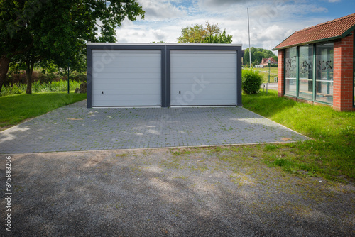 Obraz na płótnie a newly built double garage with roller doors stands under a tree w salonie