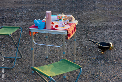 Tourist table with thermos, cups and scrambled eggs on plates. Picnic by the road during a trip.