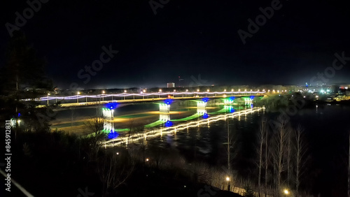 Lit-Up Bridge Over River at Night With Colorful Lights in City