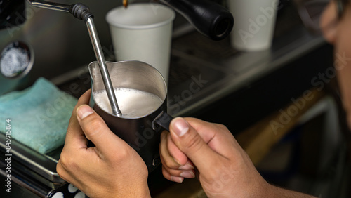 Close-up of a barista’s hands expertly frothing milk with a steam wand, coffee connoisseurs