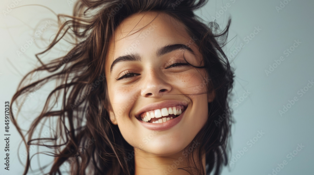 The radiant smile of a woman with tousled hair captures the essence of pure joy and warmth, set against a clean, soft-toned background. The radiant smile of a woman with tousled hair captures the essence of pure joy and warmth, set against a clean, soft-toned background.