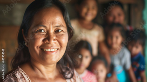 Proud smiling Filipino grandma with here family out of focus behind her. photo