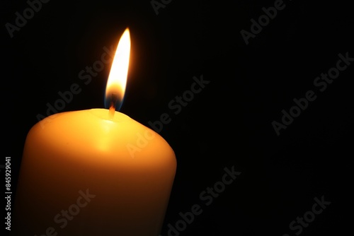 One burning church candle on black background, closeup. Space for text