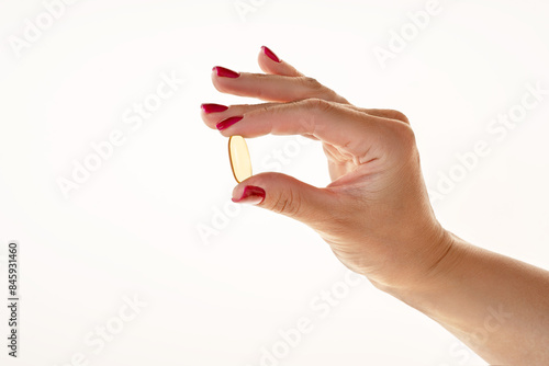 Woman holding an omega 3 capsule on a bright background photo