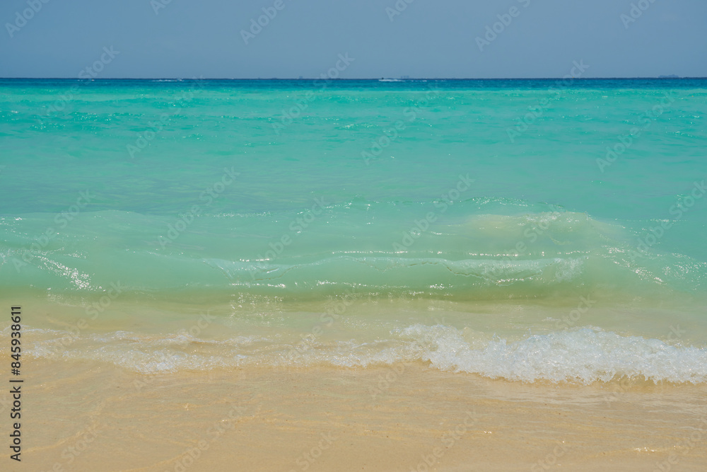 Obraz premium Waves and foam on a tropical sandy beach.