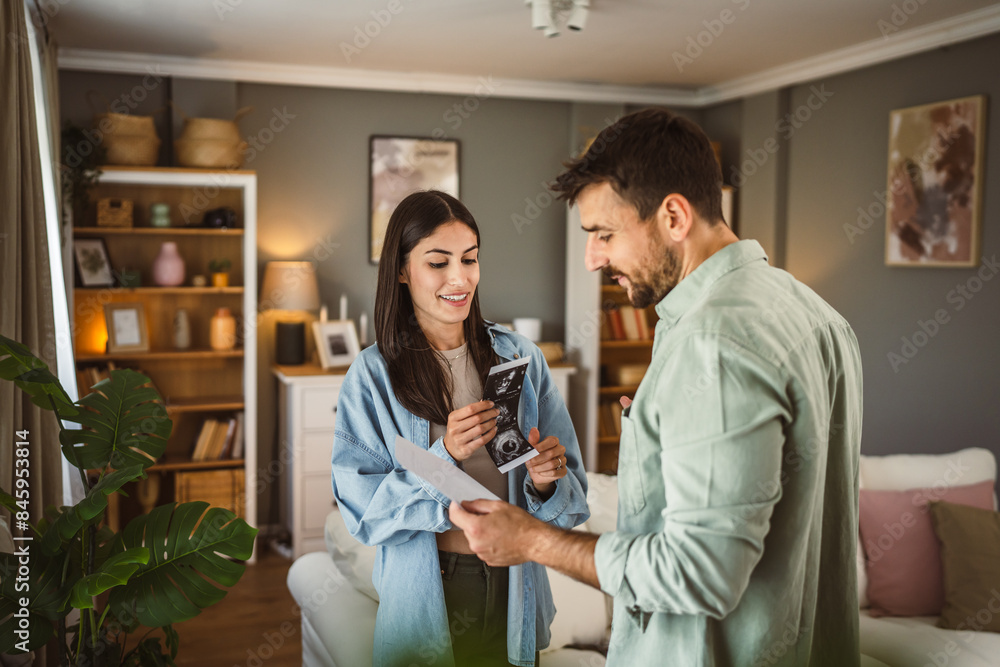 Happy pregnant woman with her husband watch ultrasound photo of baby Happy pregnant woman with her husband watch ultrasound photo of baby