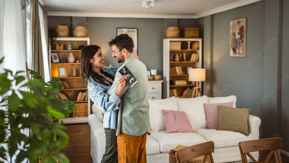 Happy pregnant woman with her husband watch ultrasound photo of baby
