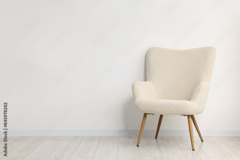 Comfortable armchair near white wall in room, space for text Comfortable armchair near white wall in room, space for text