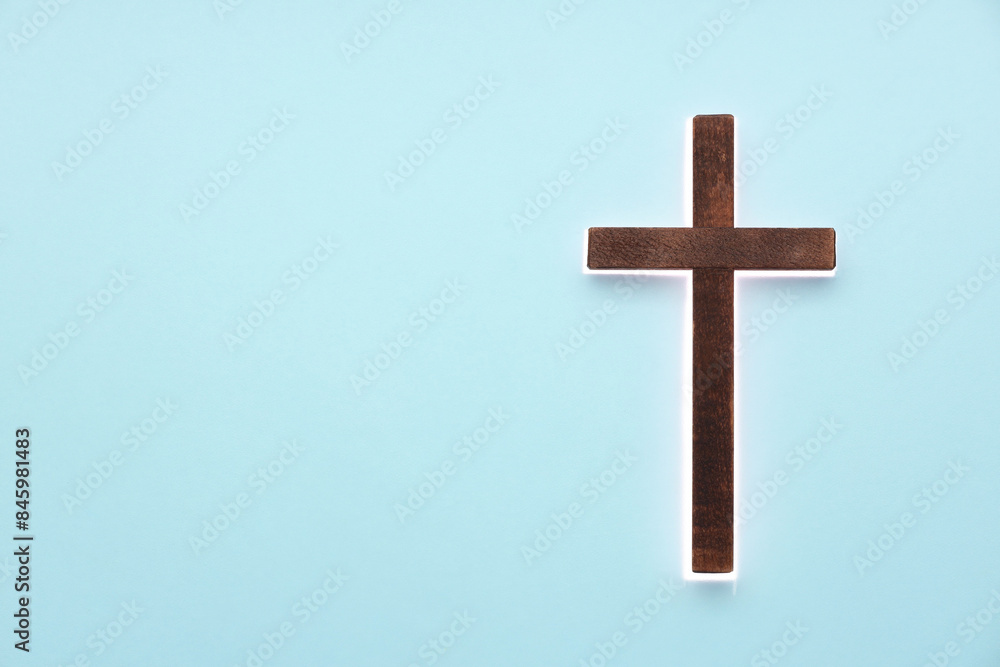 Shining cross on light blue background, space for text. Religion of Christianity