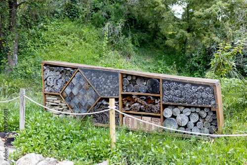 An insect hotel or bee hotel in a summer garden. An insect hotel is a human-made structure designed to offer shelter to insects of various shapes and sizes, using a range of different materials. photo