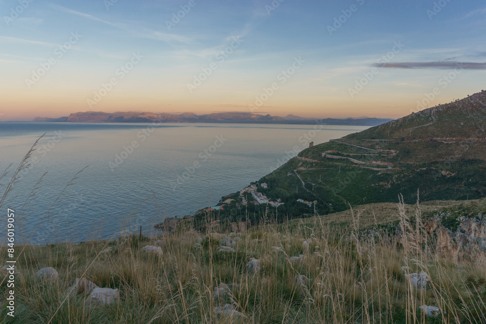 Colorful twilight after sunset with view at the coast of the mediterranean sea with curvy road at Torre dell'Impiso, San Vito lo Capo, Sicily, Italy Colorful twilight after sunset with view at the coast of the mediterranean sea with curvy road at Torre dell'Impiso, San Vito lo Capo, Sicily, Italy