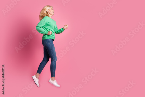 Full body photo of attractive retired woman running shopping dressed stylish green clothes isolated on pink color background © deagreez