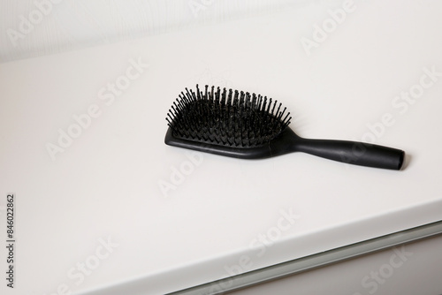 Used dirty hair brush full of hair on white table  head skin hygiene concept