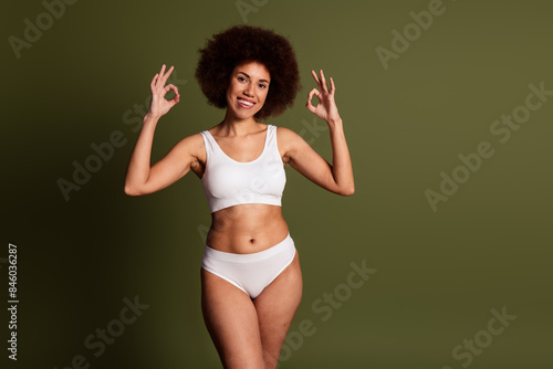 No filter photo of cute funny lady underwear lingerie enjoying girls power showing two okey signs emtpy space isolated khaki color background