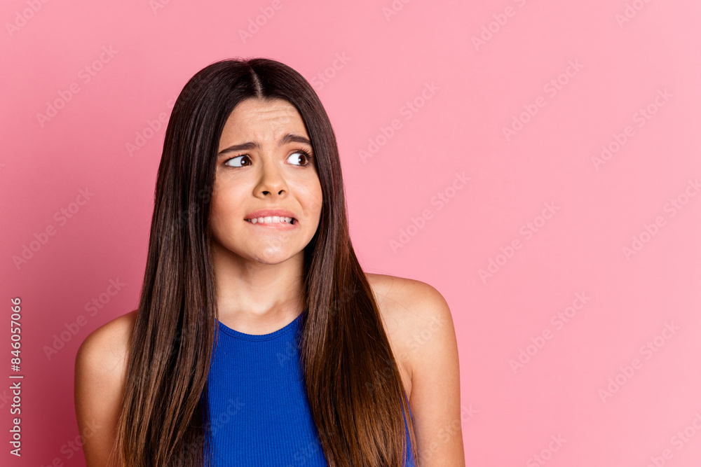Photo of pretty scared lady dressed blue top biting lip looking empty space isolated pink color background Photo of pretty scared lady dressed blue top biting lip looking empty space isolated pink color background